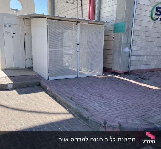 מבנה קטן עם גדר מתכת ליד קיר בניין